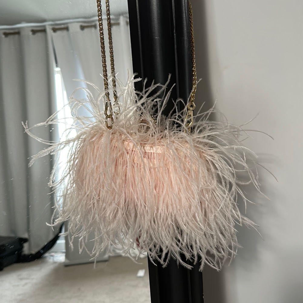 Feathery bag with ostrich feathers and gold chain. Cover table to a clutch
